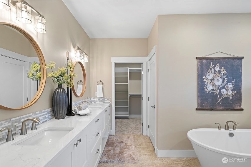 Primary bathroom with round brass mirrors and a freestanding soaking tub