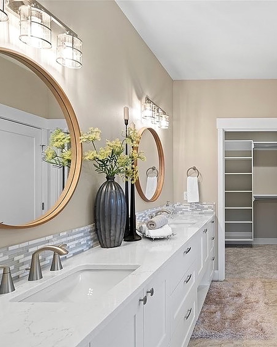 Detail of a double vanity with round mirrors and a mosaic tile backsplash